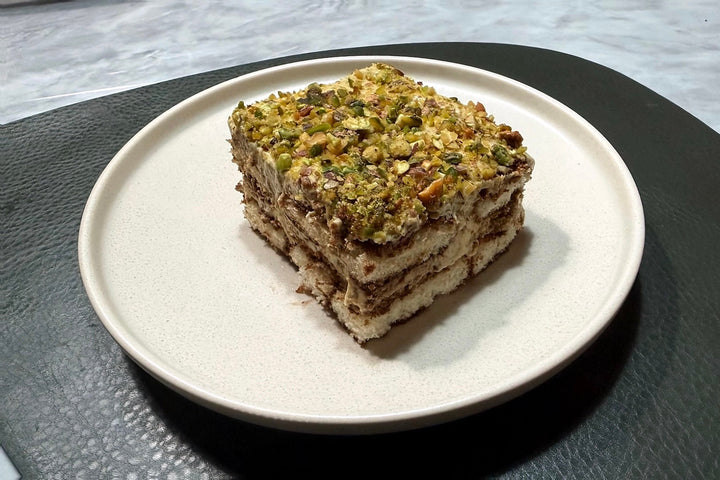 Ein Stück Pistazien-Tiramisu mit Nocissimo Pistaziencreme und gehackten Pistazien auf einem Teller